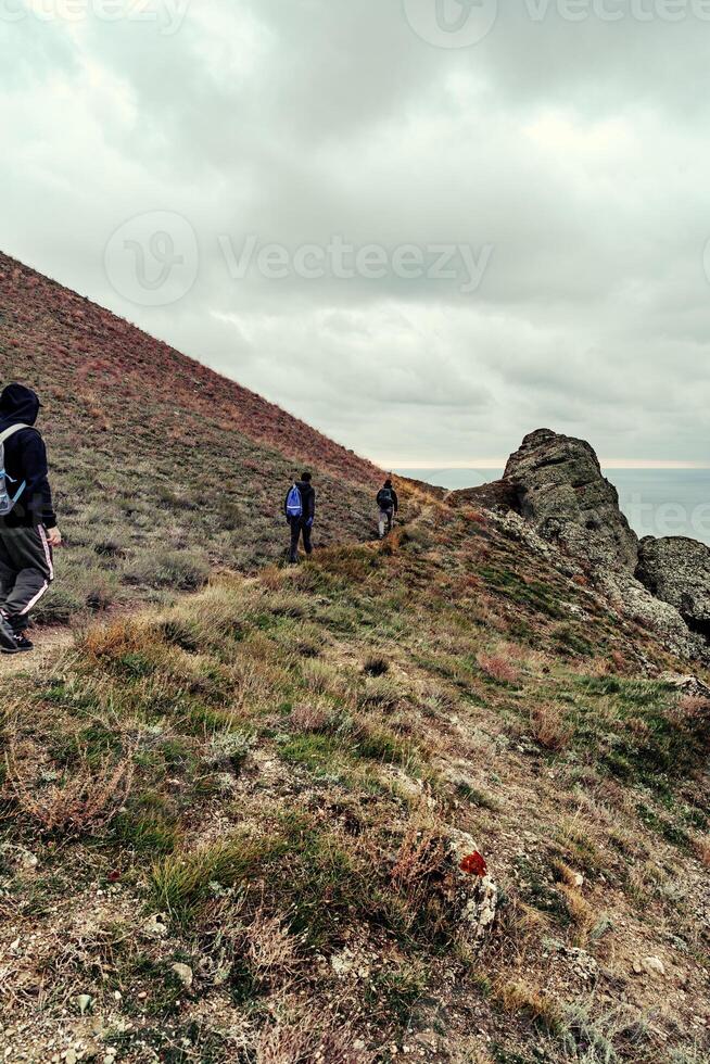 Hikers explore rugged terrain near the coast on an overcast day in a remote location photo