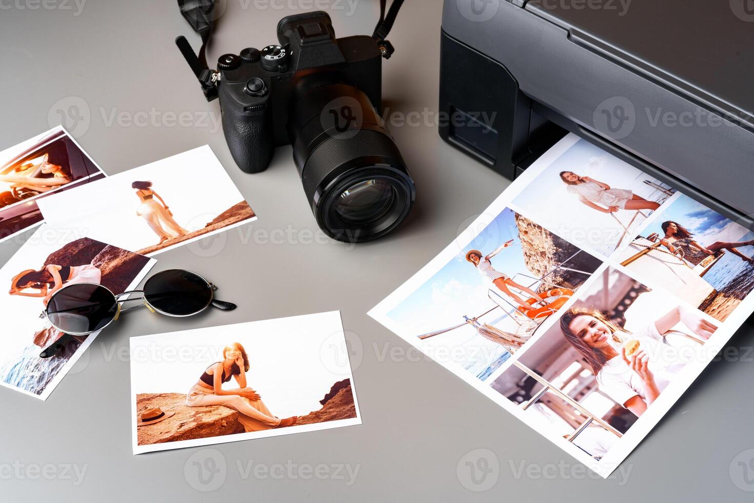 Photo camera with colorful printer photos on gray desk