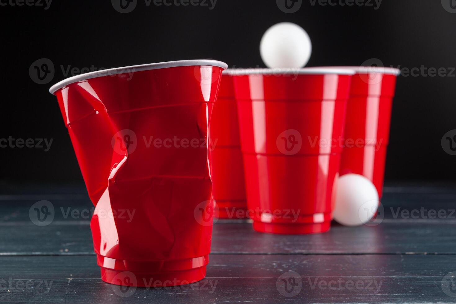 Wooden table with red cups and ball for beer pong photo