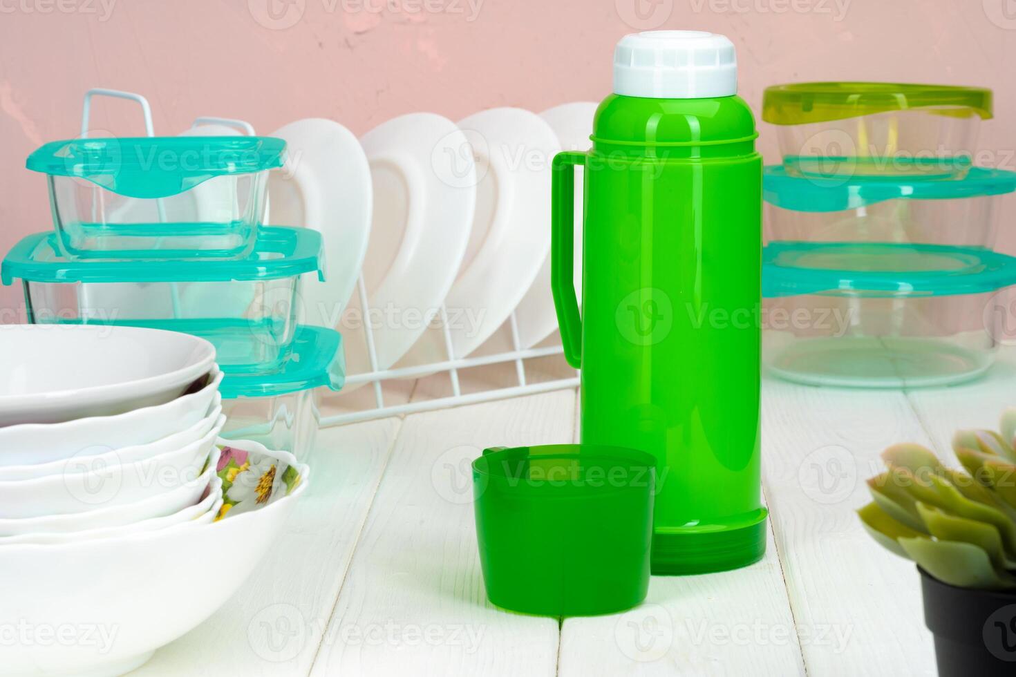 Thermos bottle against tableware in a kitchen photo