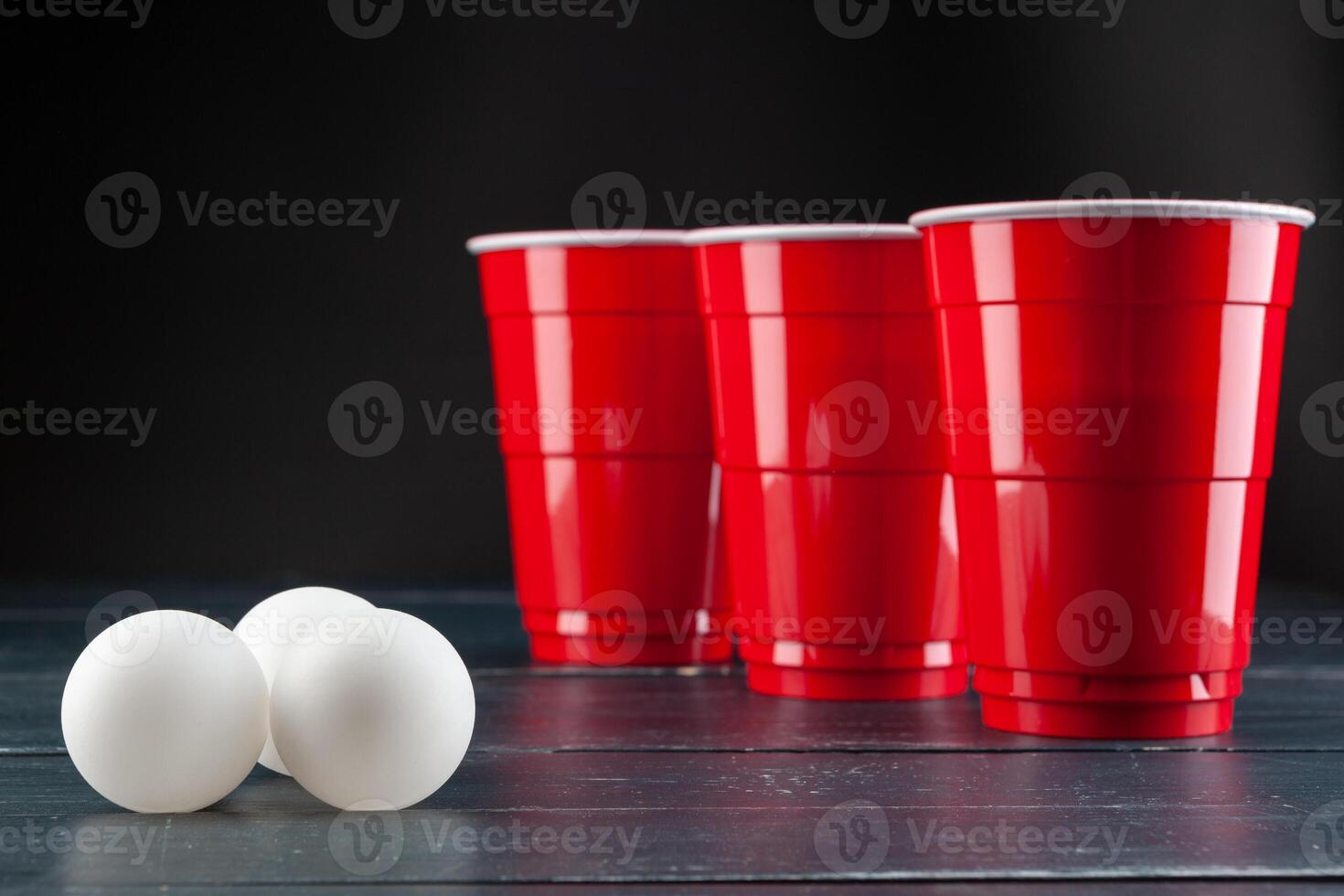 Wooden table with red cups and ball for beer pong photo