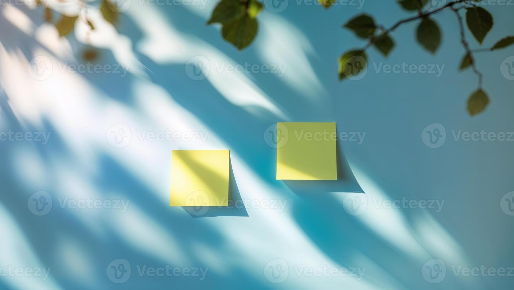 Yellow sticky notes on a blue wall casting shadows from leaves in natural light photo