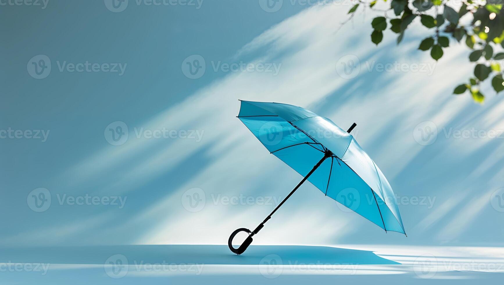 Umbrella leaning against a blue backdrop with soft shadows and green leaves in a serene setting photo