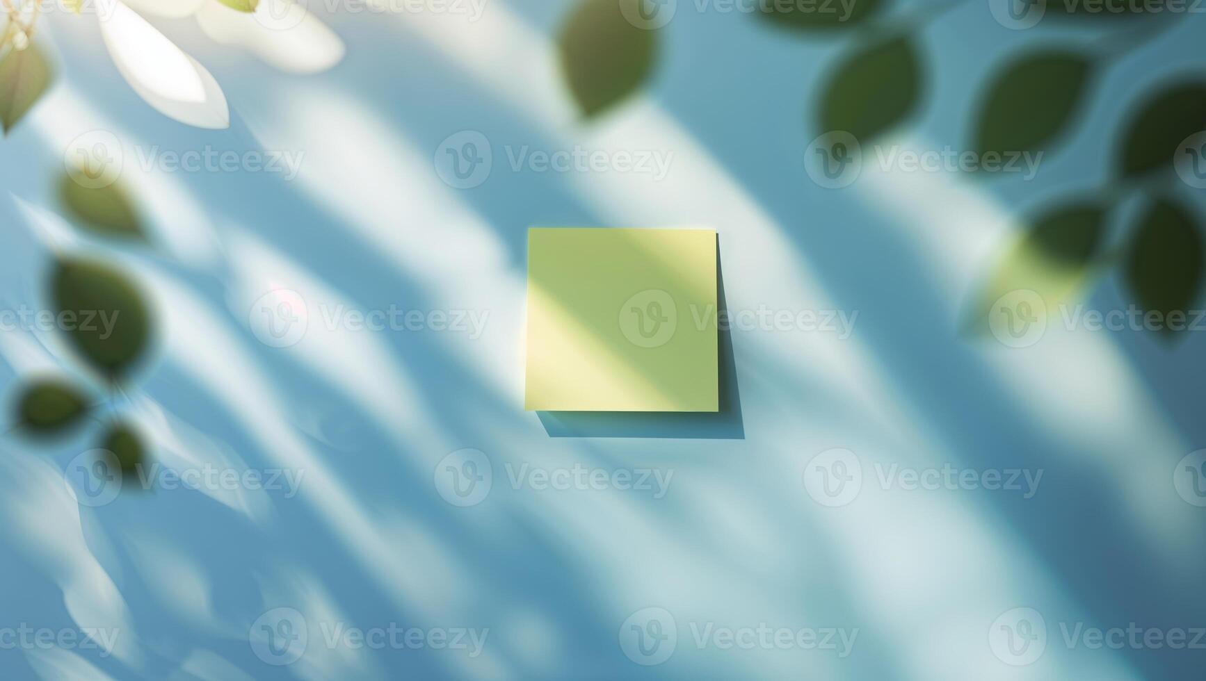 Sticky note on a blue wall with shadows from green leaves created by sunlight in a bright room photo