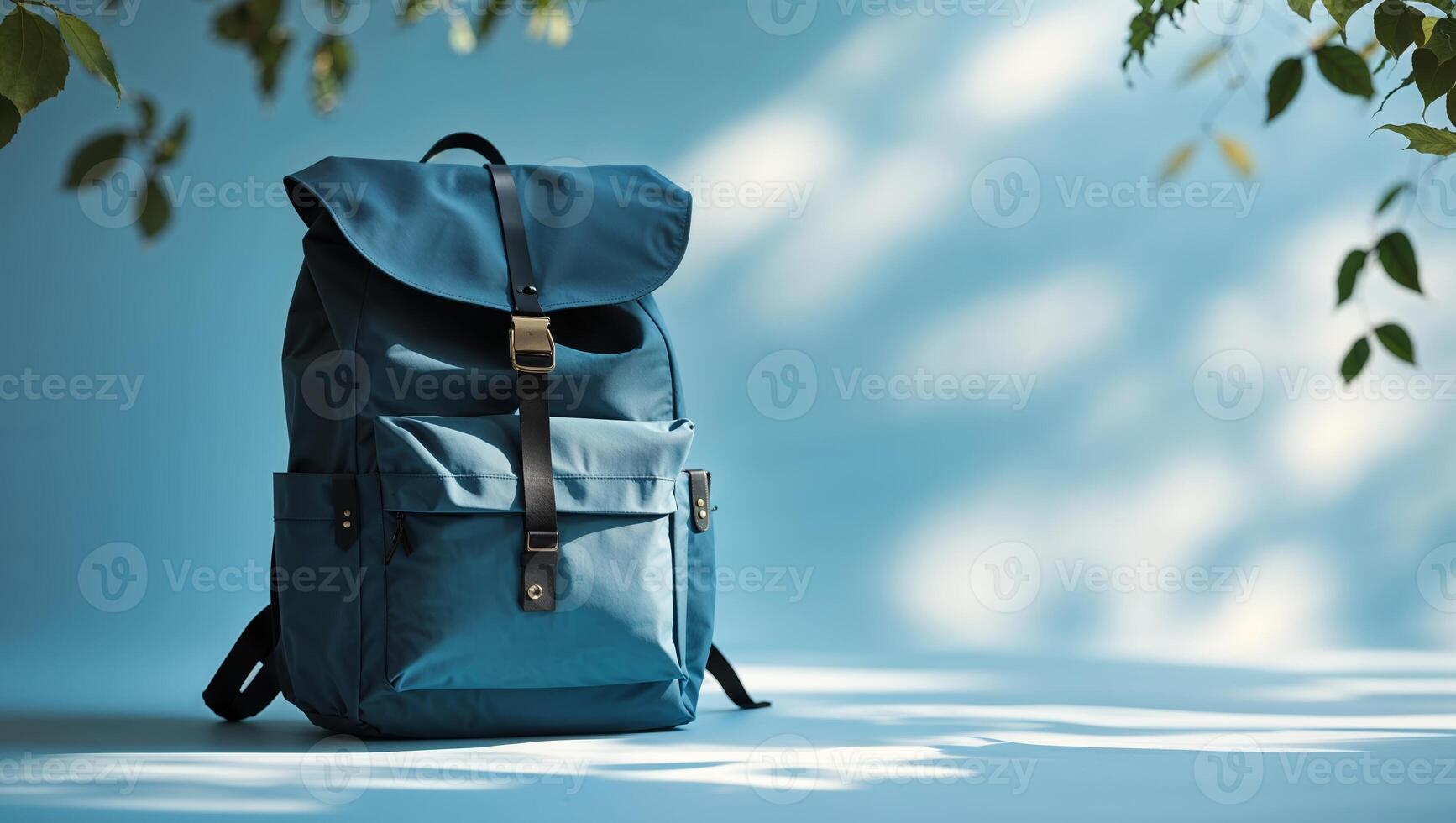 Stylish blue backpack resting on a light blue surface with soft shadows from leaves in the background photo
