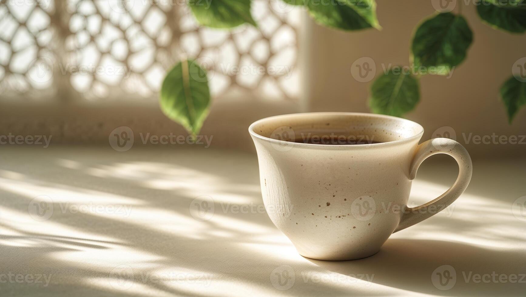 Warm cup of coffee resting on a table with shadows and green leaves in a serene indoor setting photo