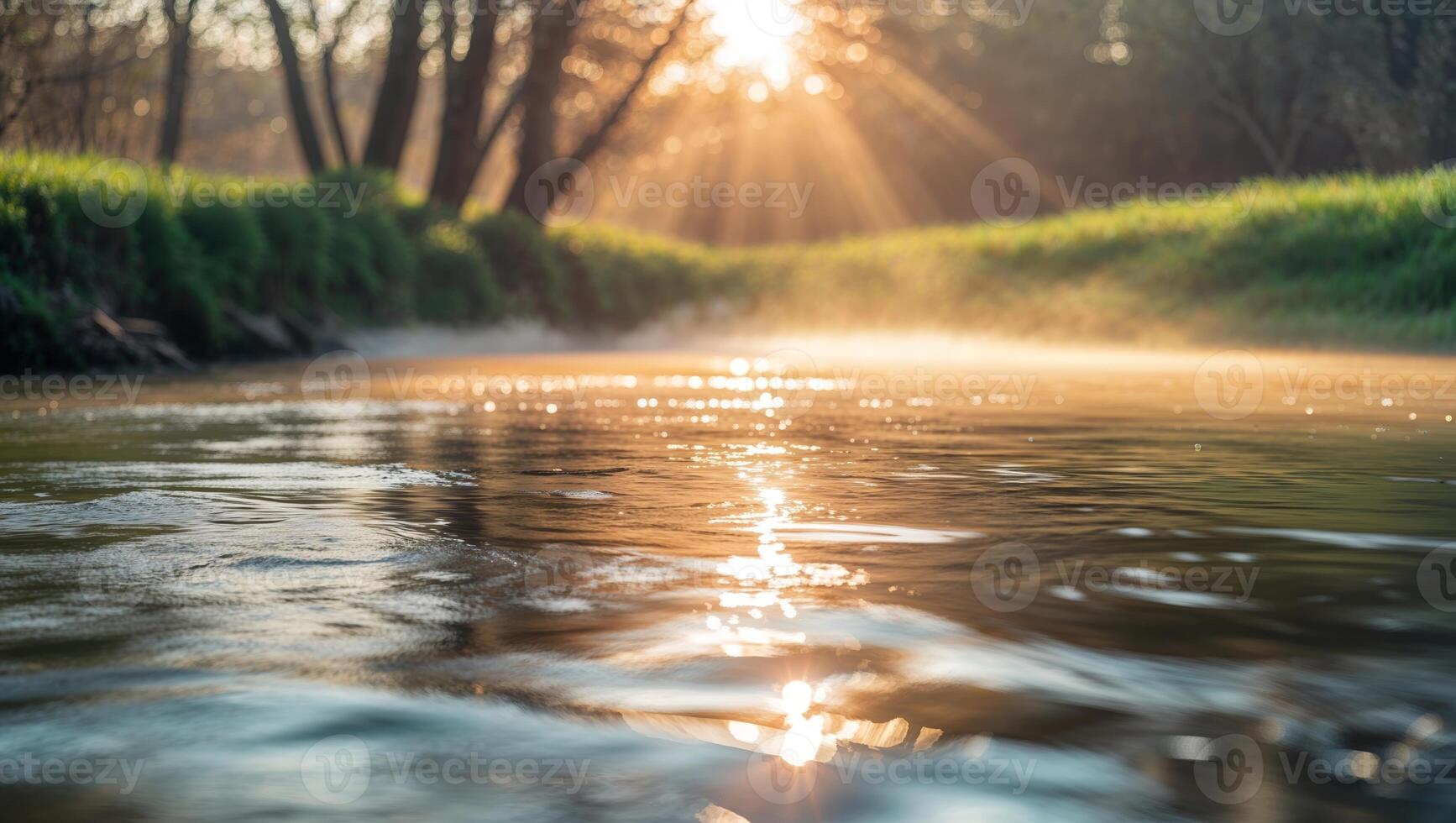 Mist rises over a reflective stream at sunrise surrounded by lush greenery photo