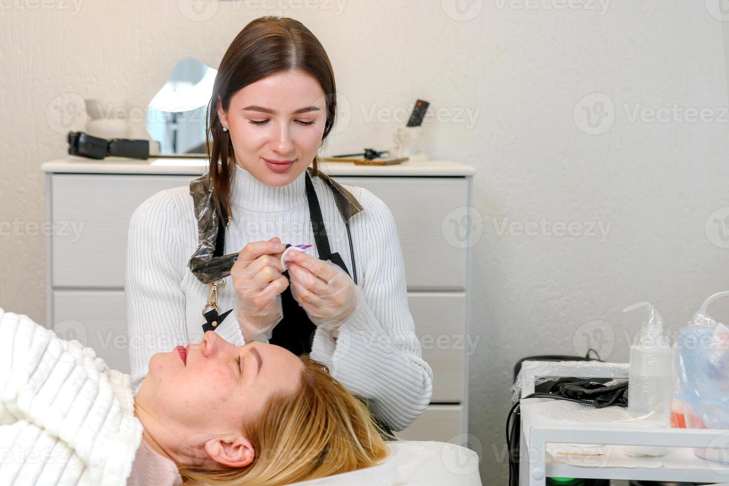 permanent makeup artist wipes the tool before working with a client photo
