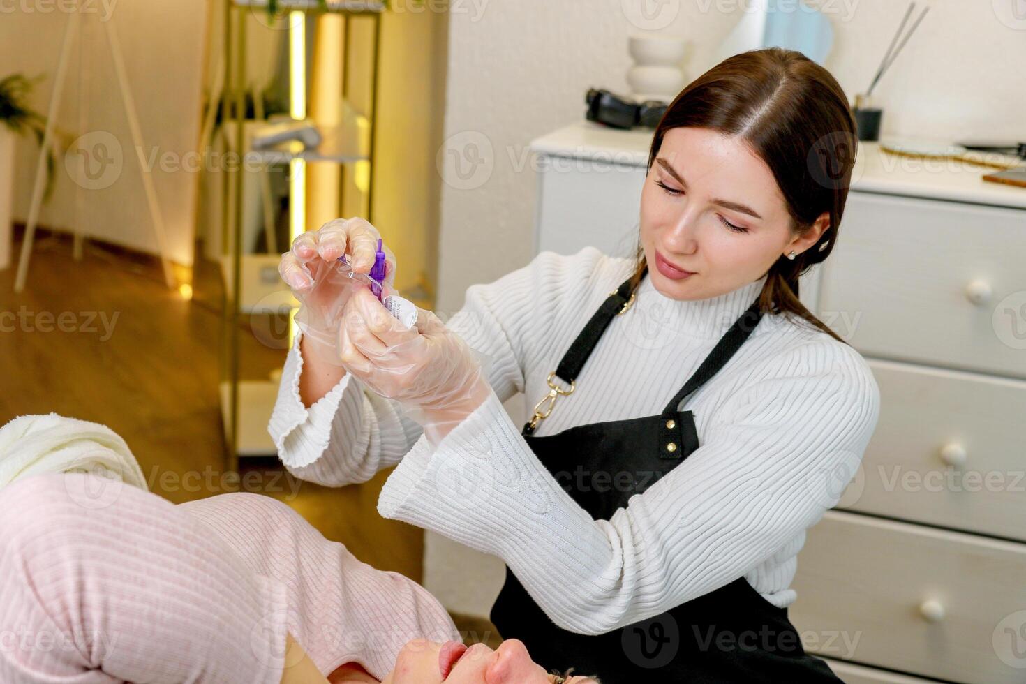 a pretty girl permanent makeup artist opens disposable tools for the client that she will use photo