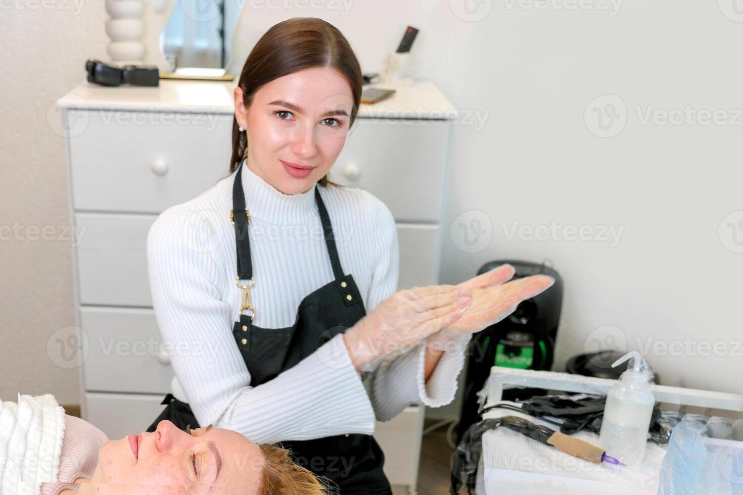 cute permanent makeup artist disinfects her hands before starting work with a client photo