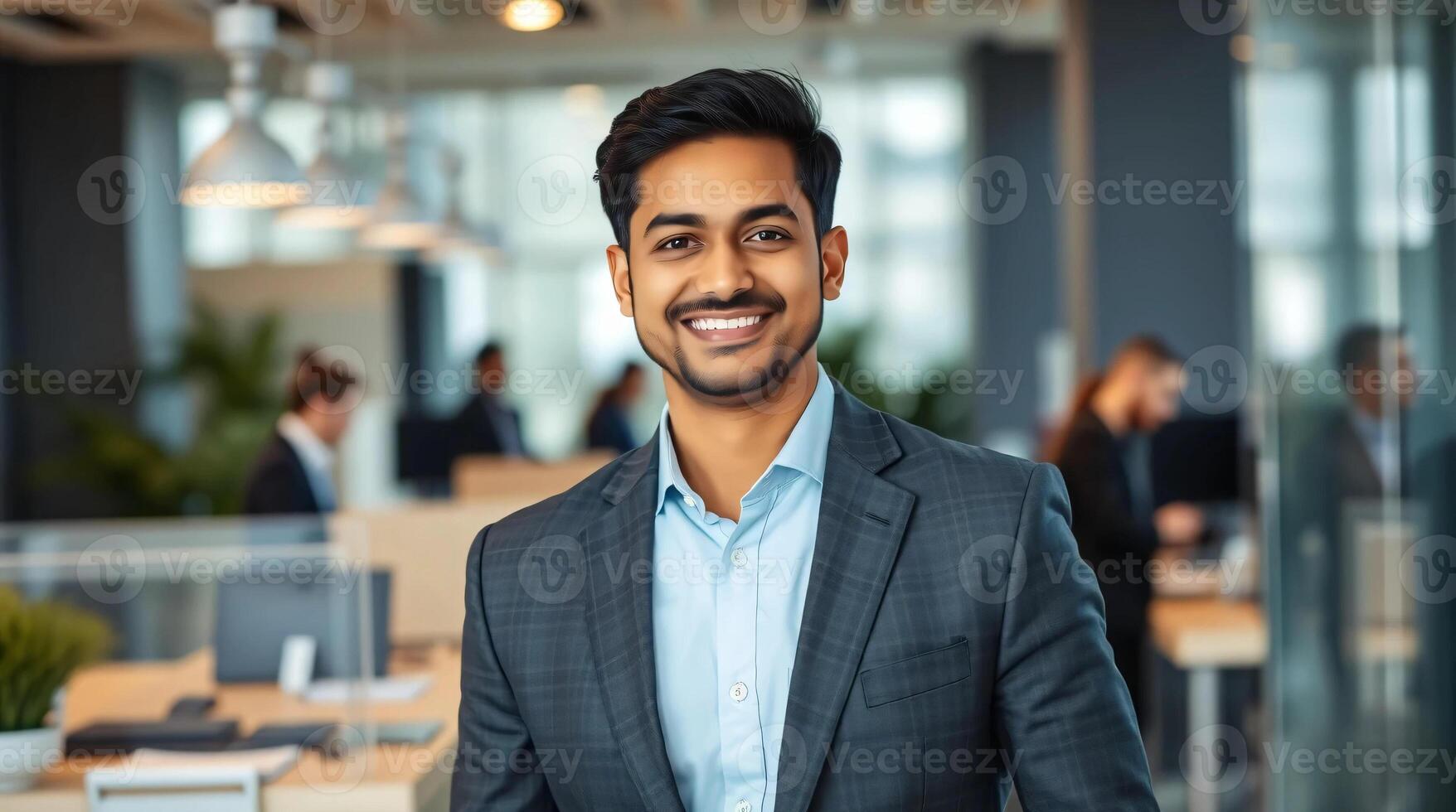 A young indian man in a suit and tie standing in an office photo