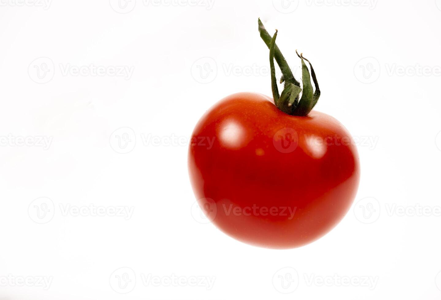 Fresh red tomato suspended against a white background in soft light photo
