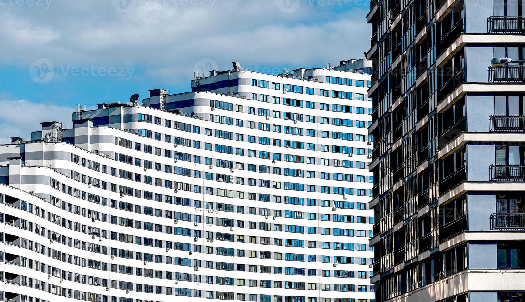 Tall modern high-rise condominium in downtown city. Geometric, wavy facade with windows offering photo