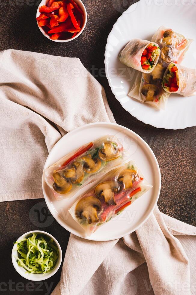 Delicious spring rolls with vegetables and mushrooms in rice paper on a plate top and vertical view photo