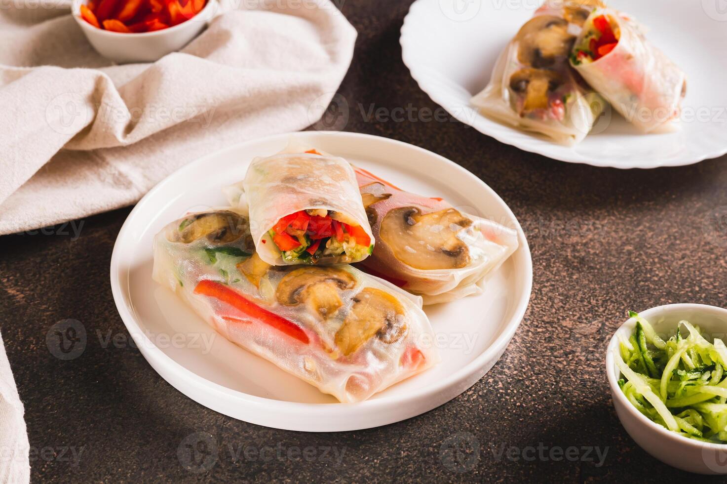 Delicious spring rolls with vegetables and mushrooms in rice paper on a plate on the table photo