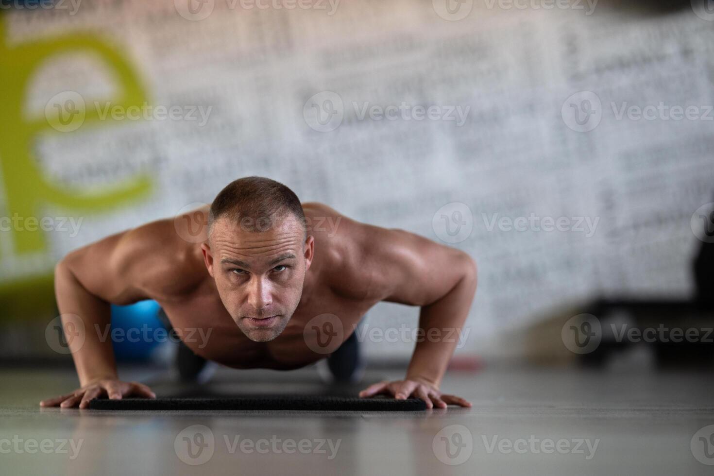 A muscular man performing push ups in the gym, showcasing strength, endurance, and dedication to his fitness routine. photo