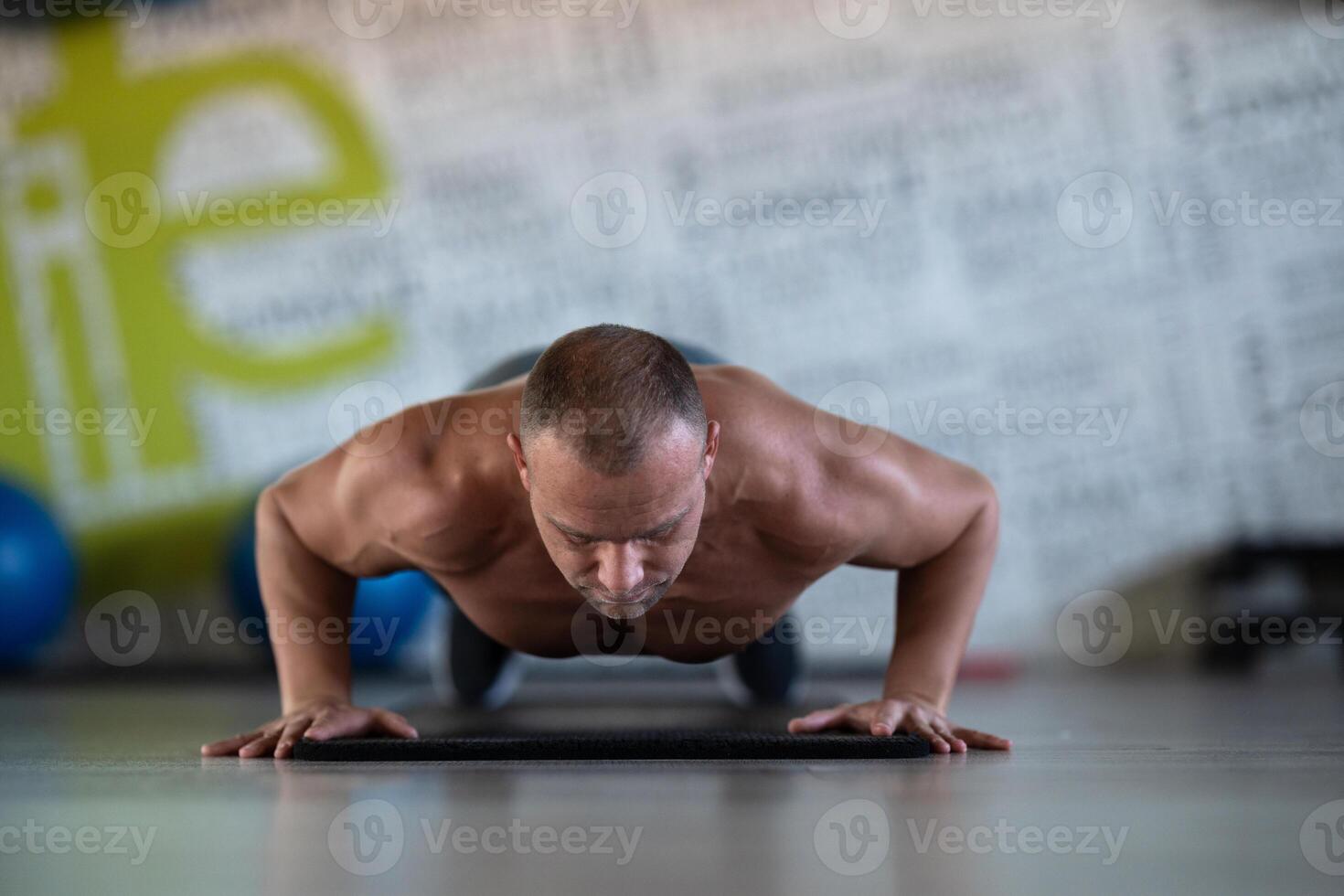 A muscular man performing push ups in the gym, showcasing strength, endurance, and dedication to his fitness routine. photo