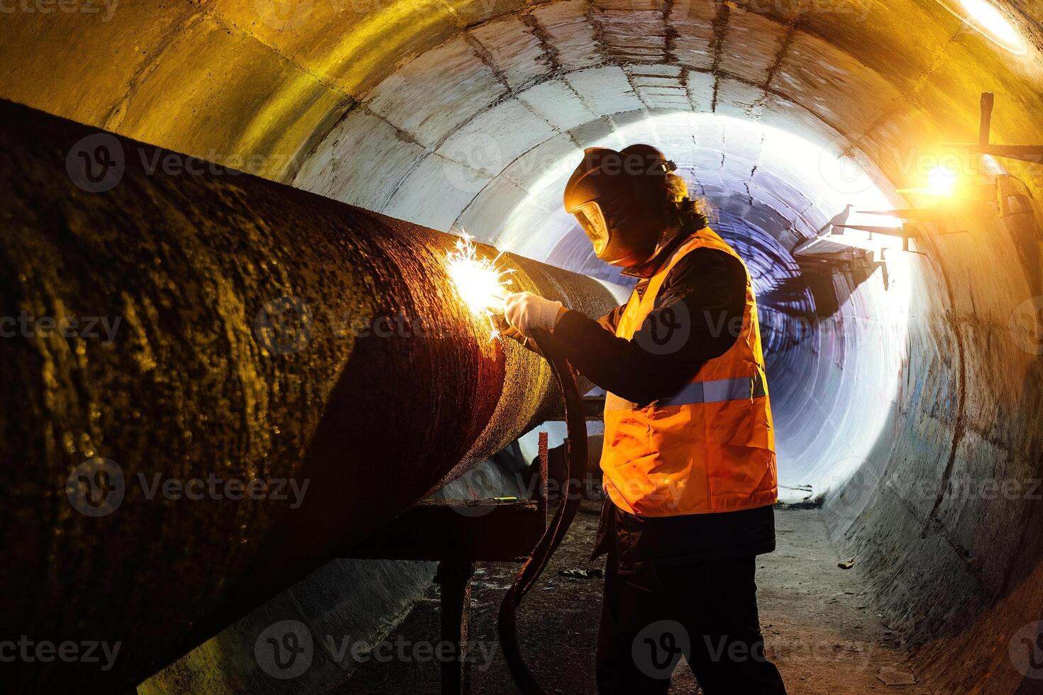 Worker in protective mask welding pipe in tunnel photo