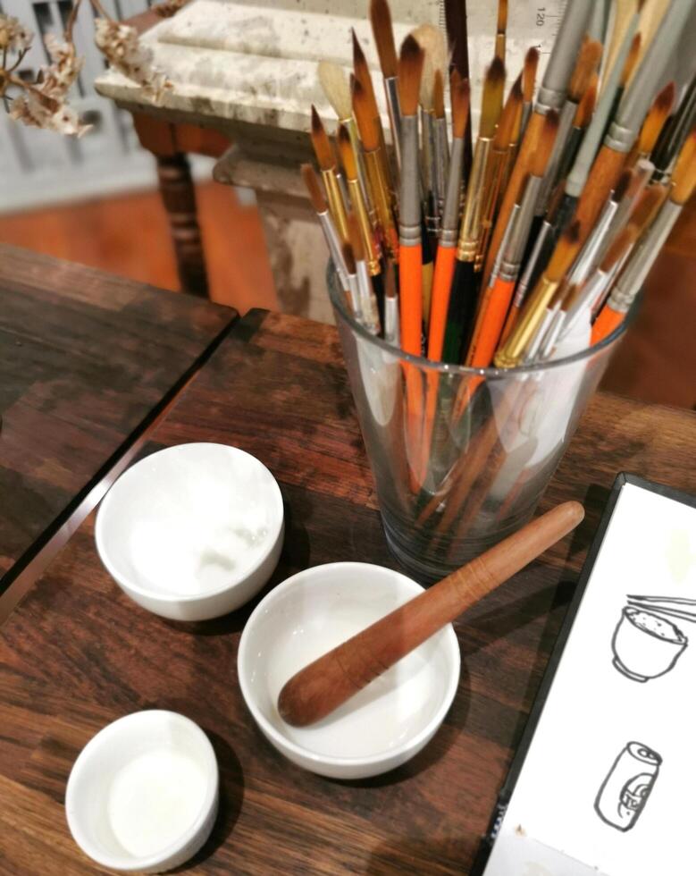 A table with paint brushes, paint and a book photo