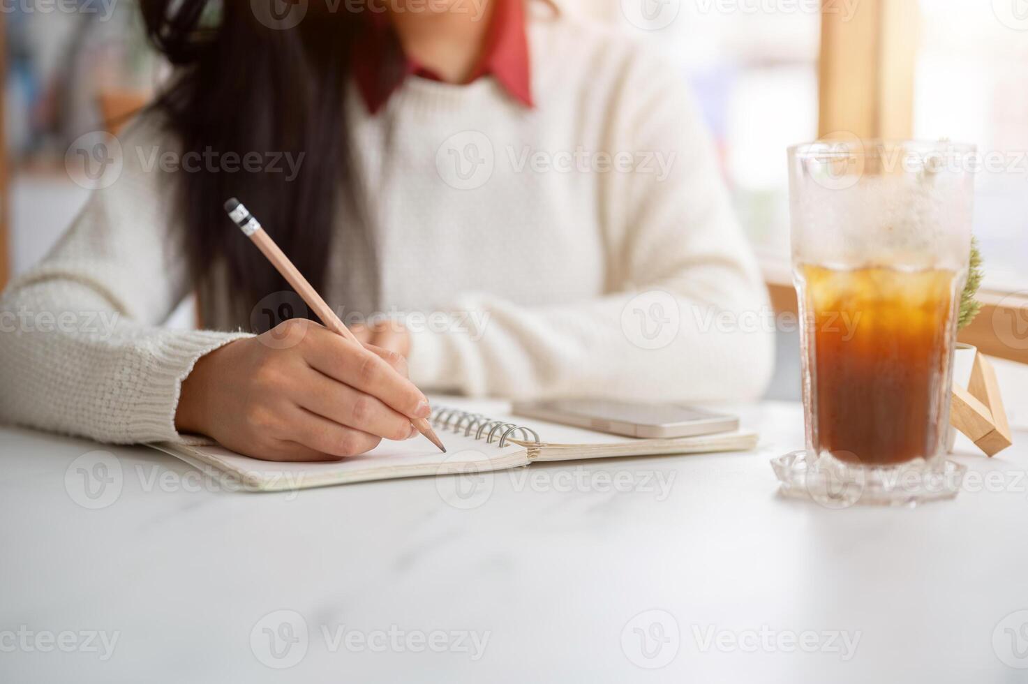 A close up of a woman hand holding a pencil and writing in the notebook, Working or study in the cafe. photo