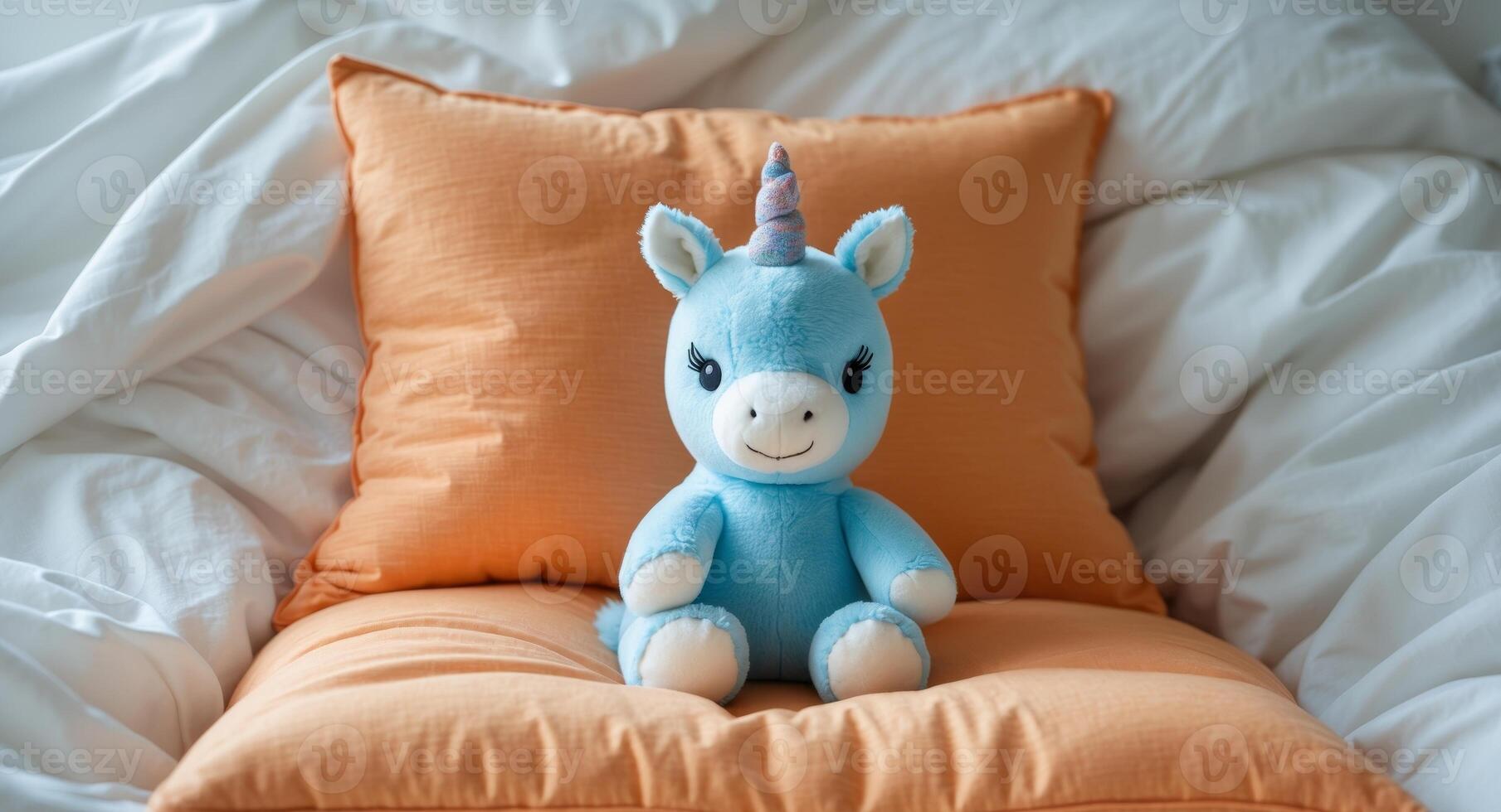 Adorable Blue Unicorn Stuffed Animal On Bed With Orange Pillows. photo