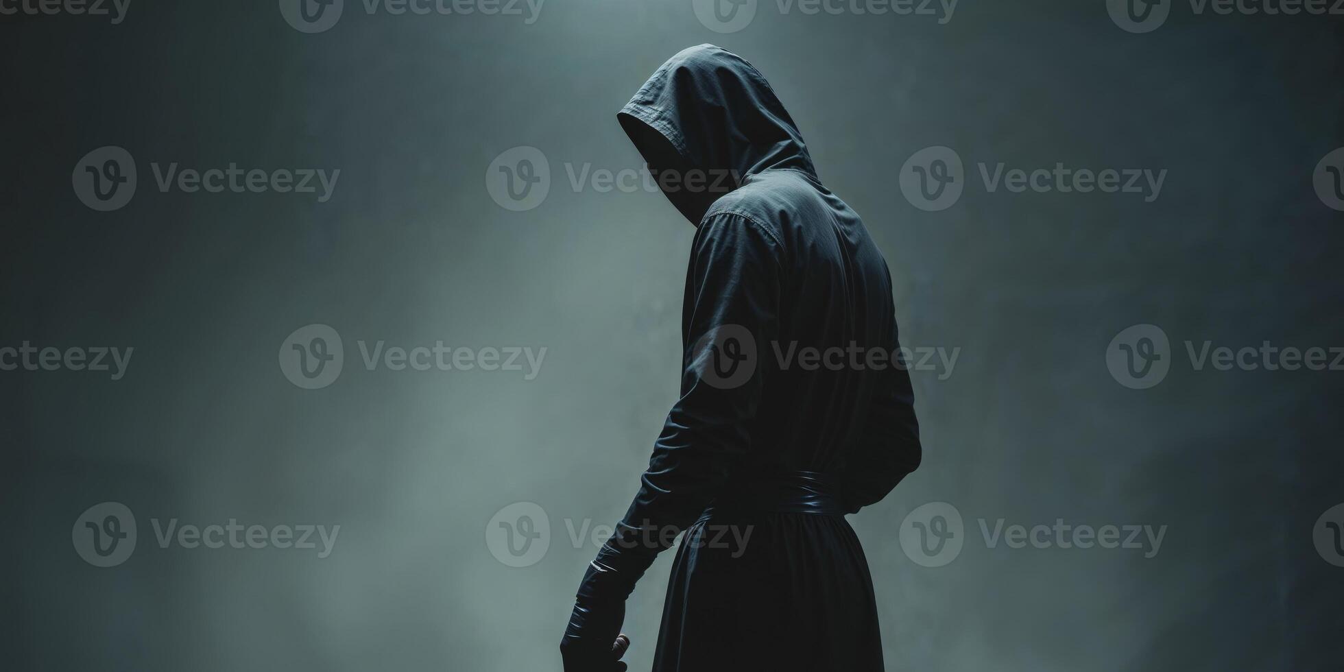 A man in a hooded robe standing in the dark photo
