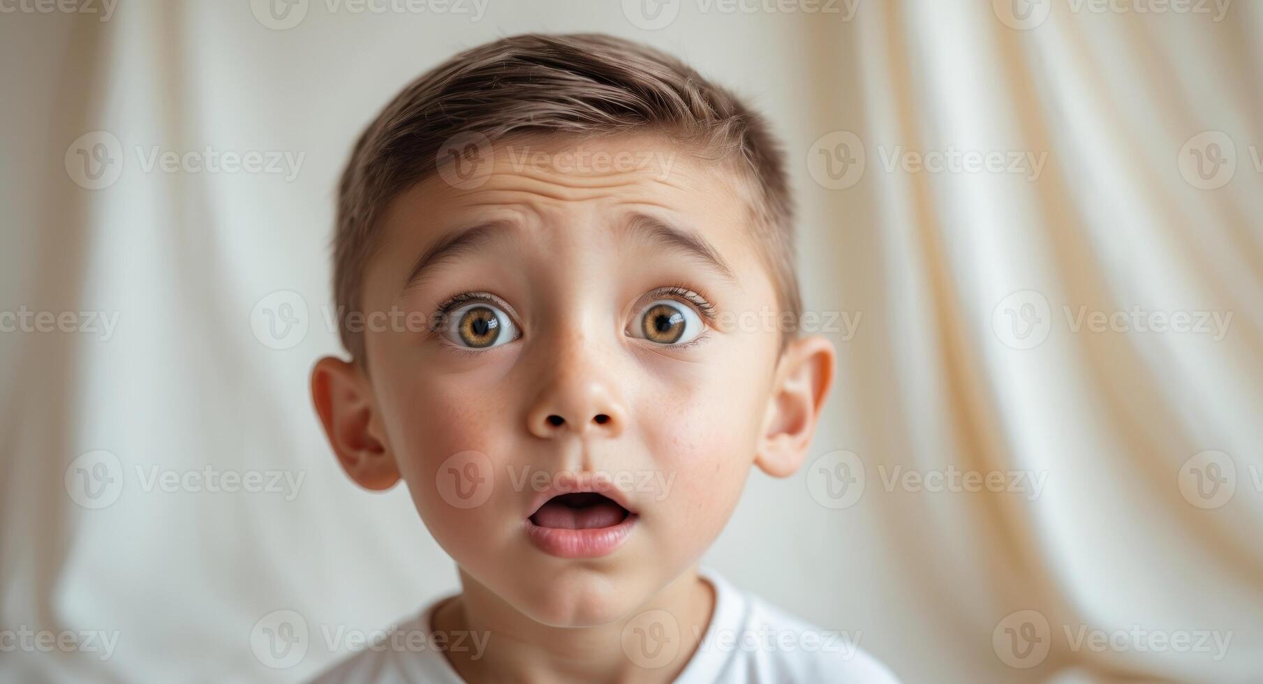 A surprised young boy with wide eyes looks directly forward photo