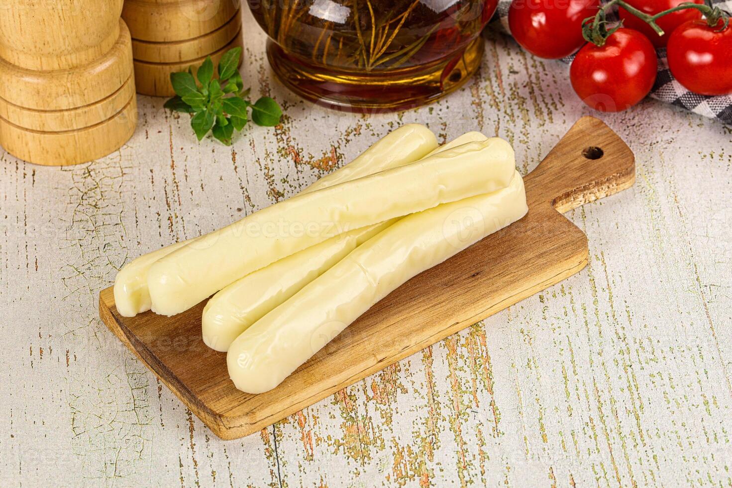 A wooden cutting board with cheese sticks on it photo