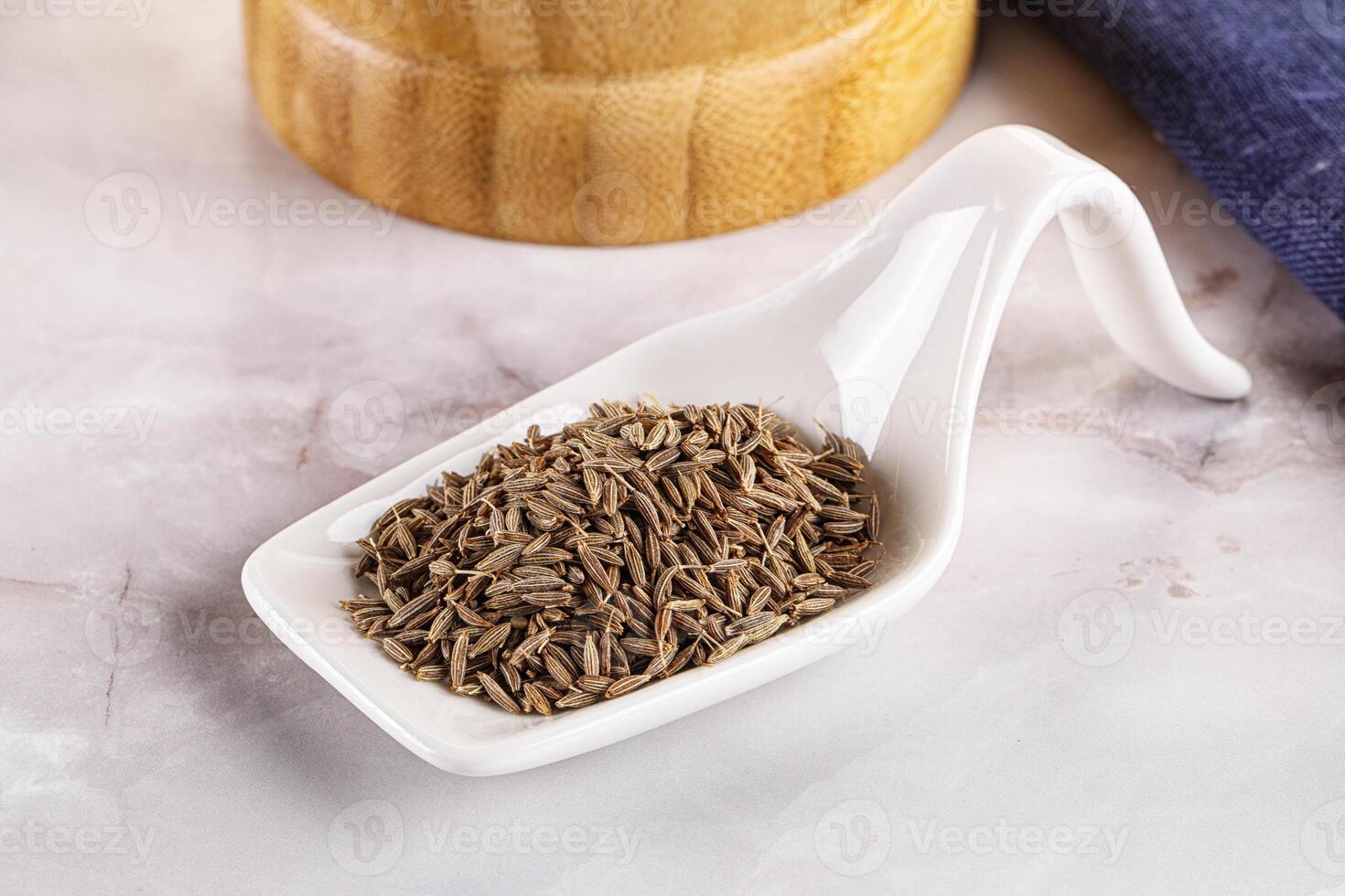 Cumin seeds in a white scoop on a marble counter photo