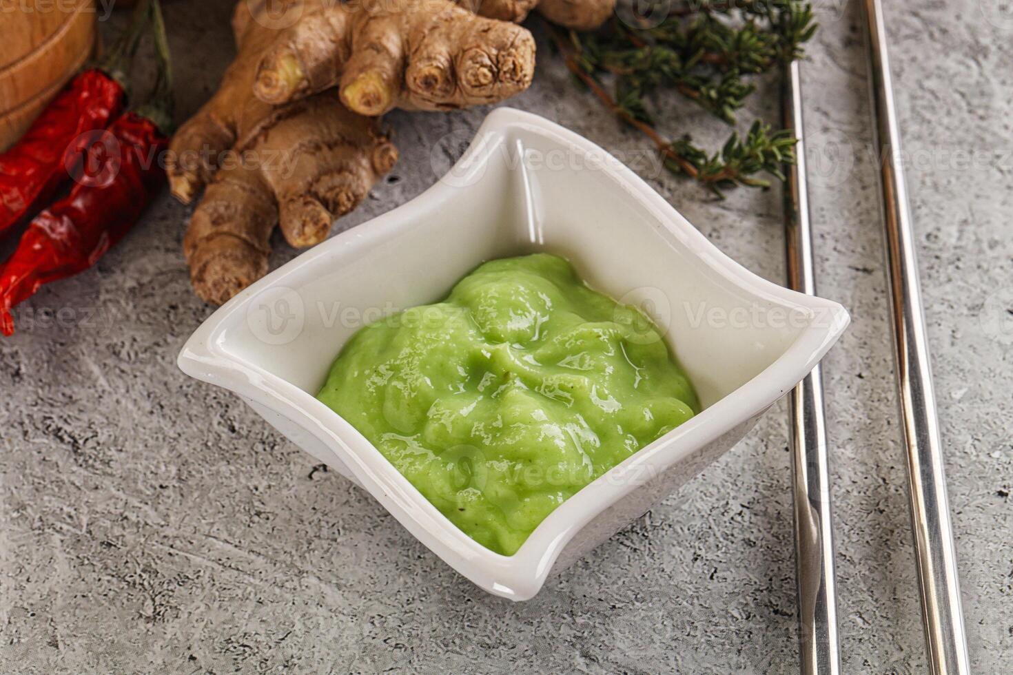 A bowl of green sauce next to a bowl of ginger photo
