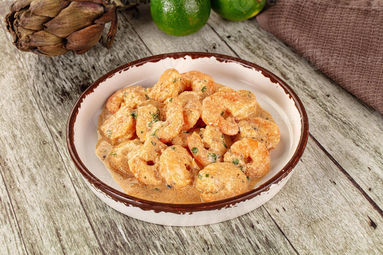 A bowl of shrimp and a lime on a wooden table photo