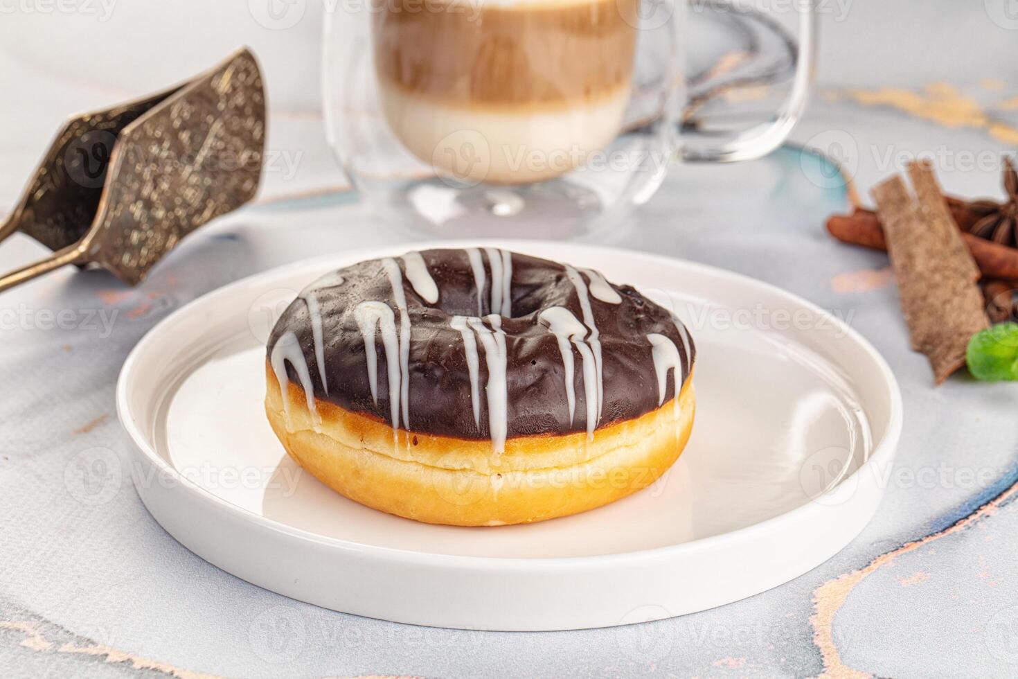 A donut on a plate with a cup of coffee and cinnamon photo