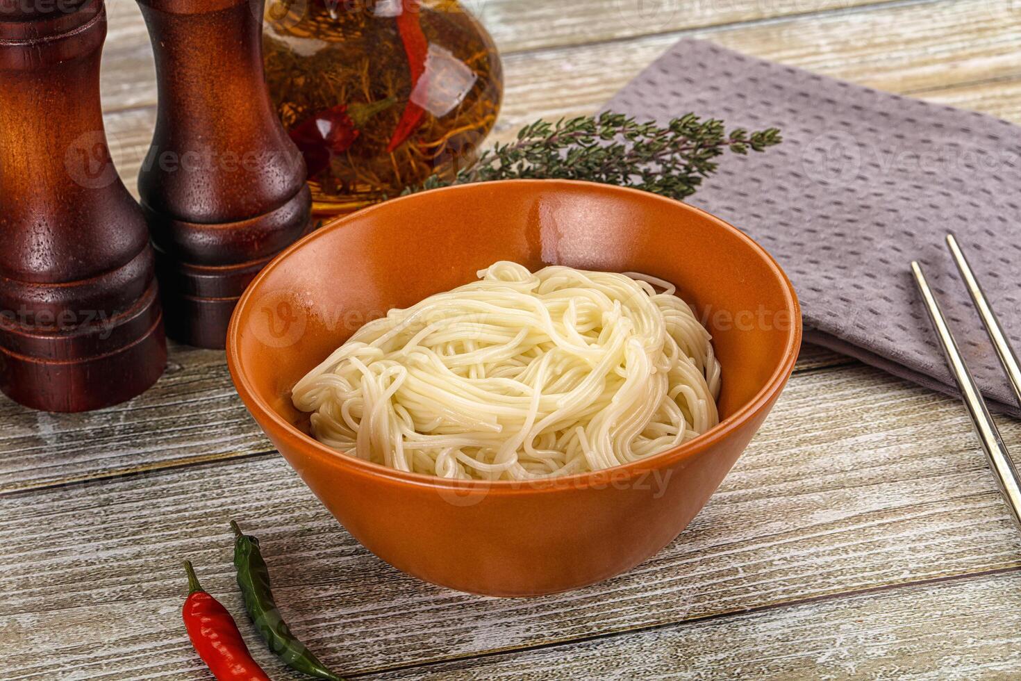 A bowl of noodles with chopsticks and spices photo