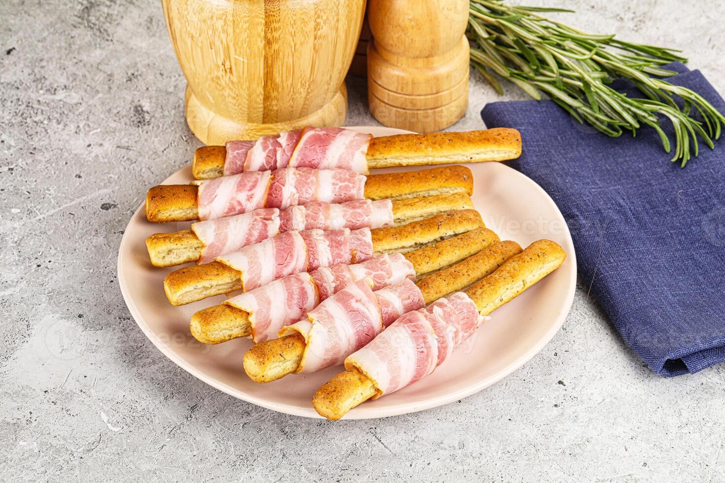 A plate topped with bacon wrapped bread sticks photo