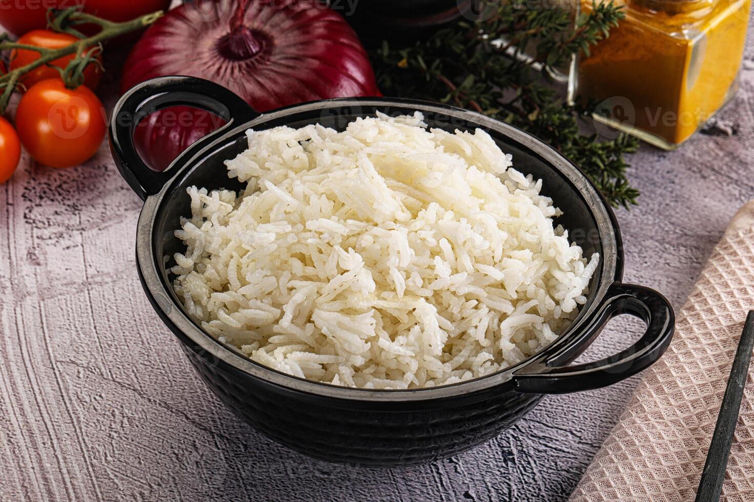 A bowl of white rice sits on a table next to other ingredients photo