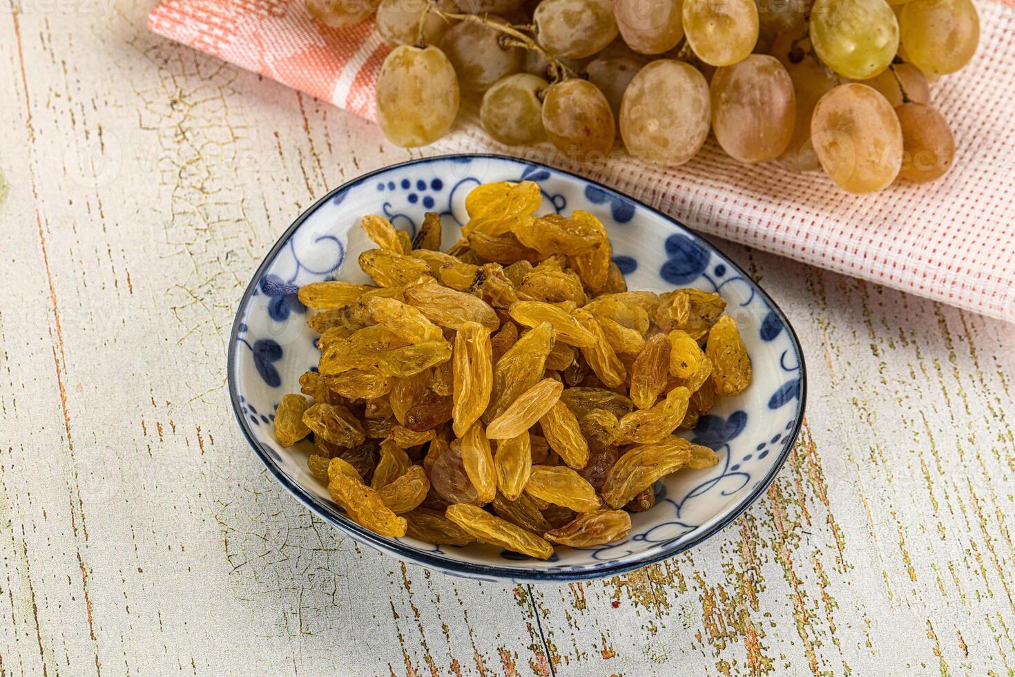 A bowl of raisins and a plate of grapes photo