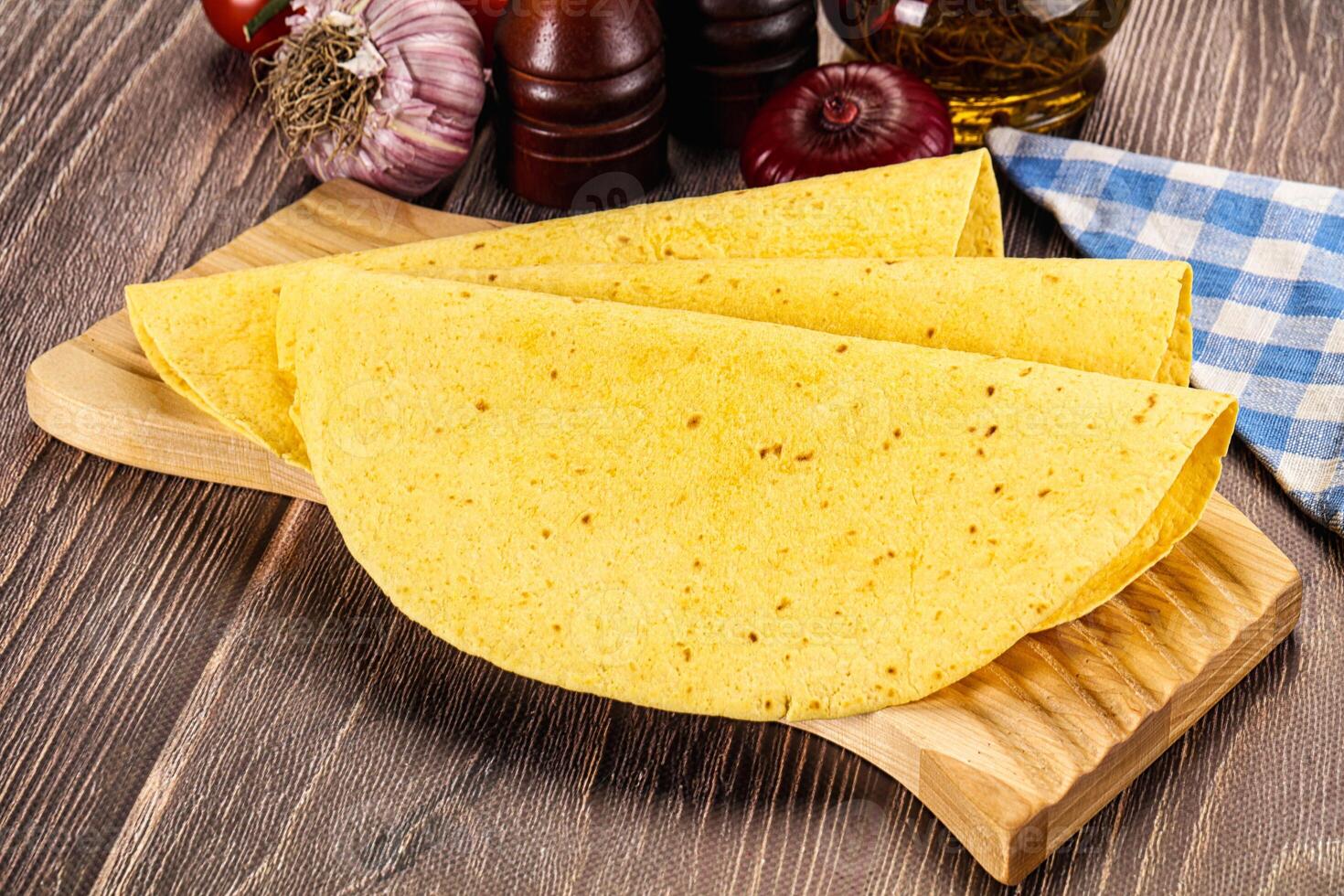 A wooden cutting board with tortillas, tomatoes, and other ingredients photo