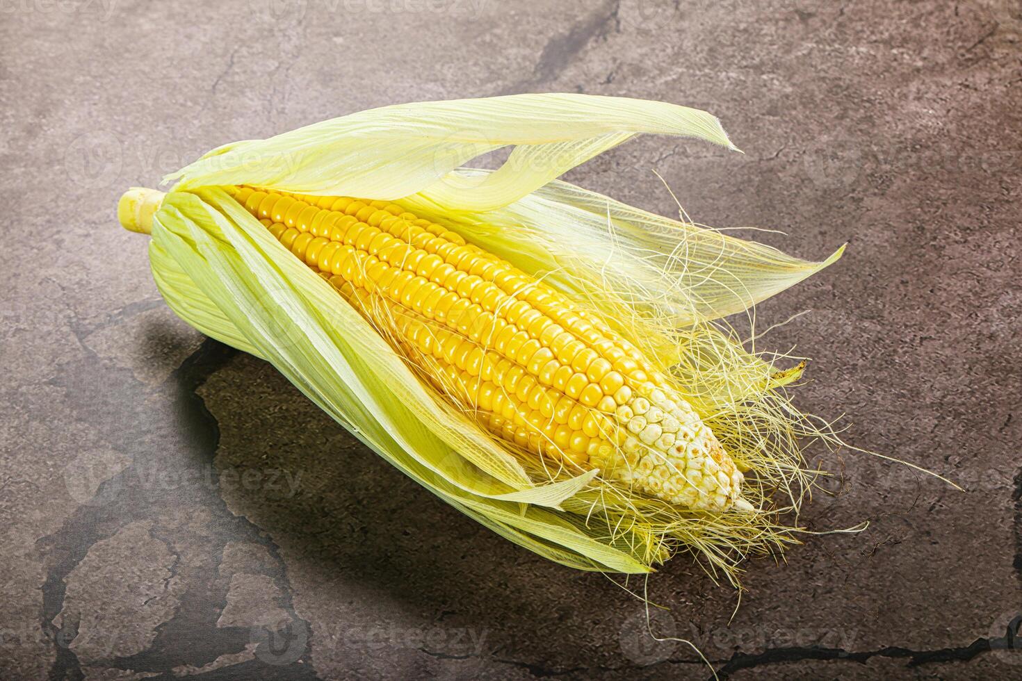 A corn on the cob on a concrete surface photo