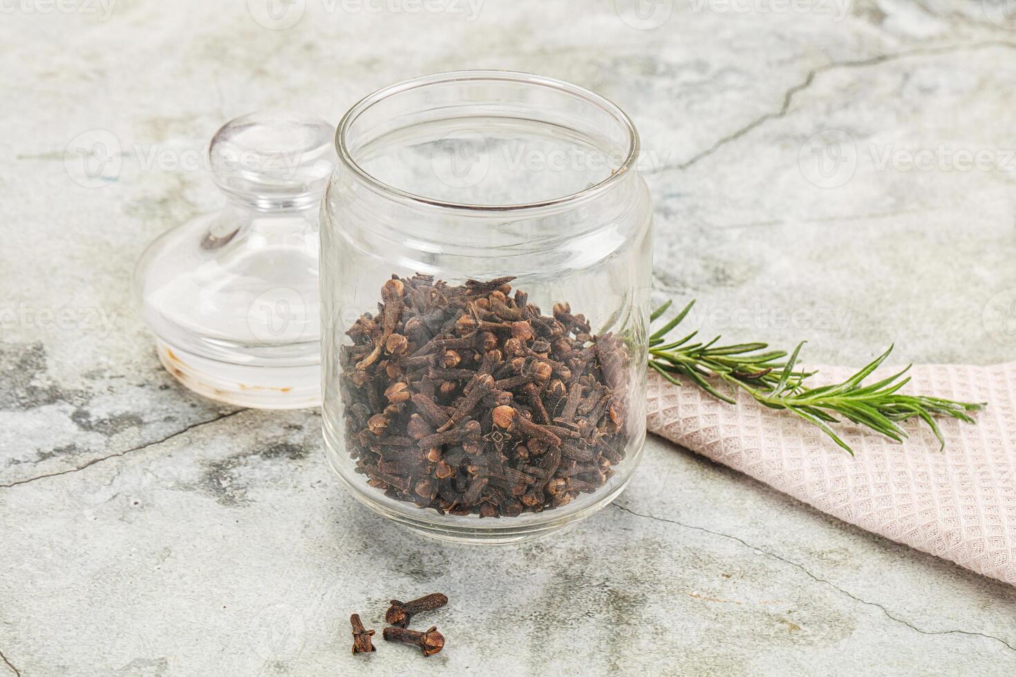 A jar of dried herbs and a glass bottle with a sprig of rosemary photo