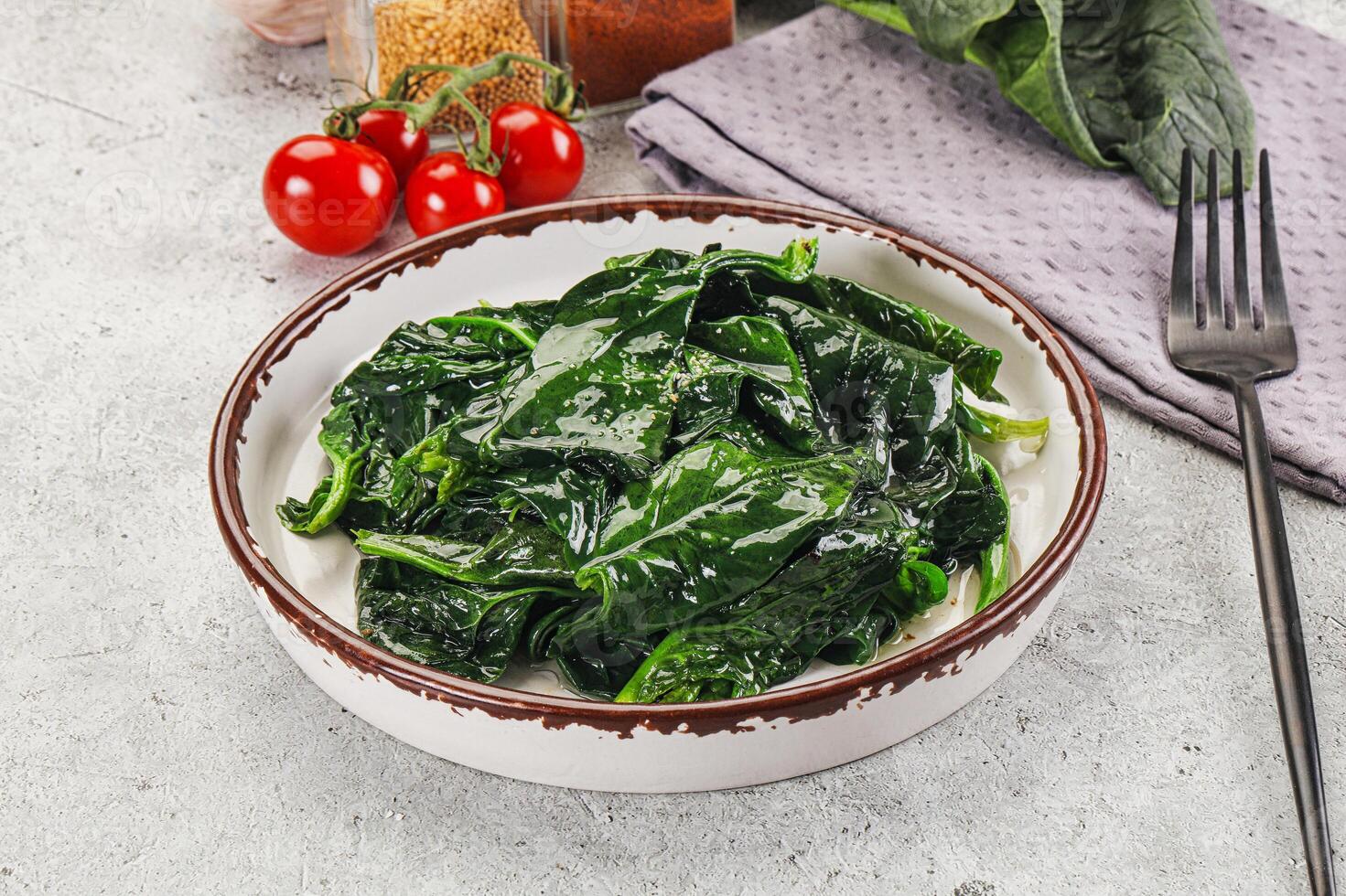 A bowl of spinach with a fork and a knife photo