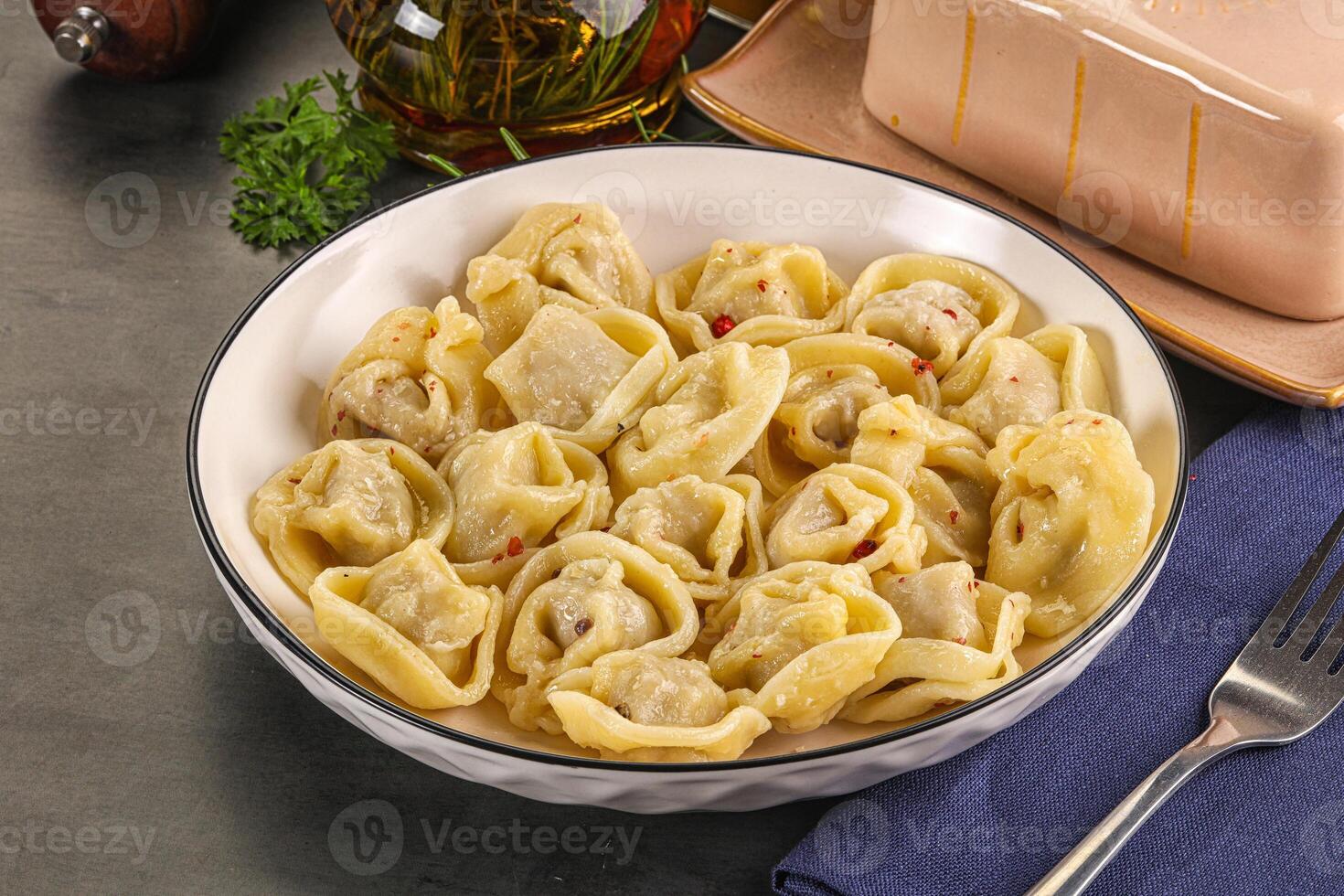 A bowl of pasta with a fork and a bottle of wine photo