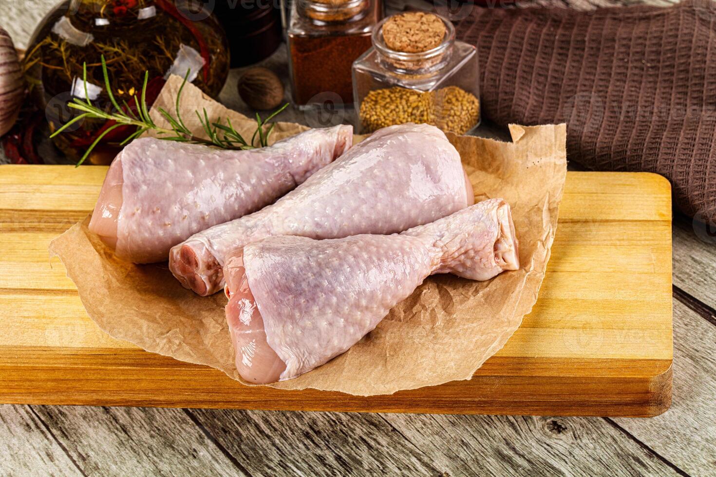 A wooden cutting board with chicken legs and spices photo