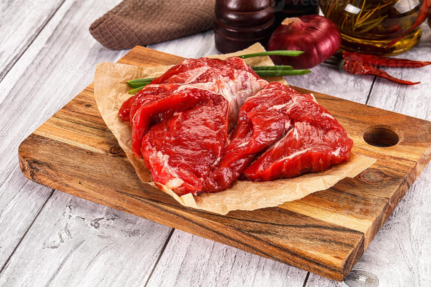 Raw beef on a cutting board with spices and other ingredients photo