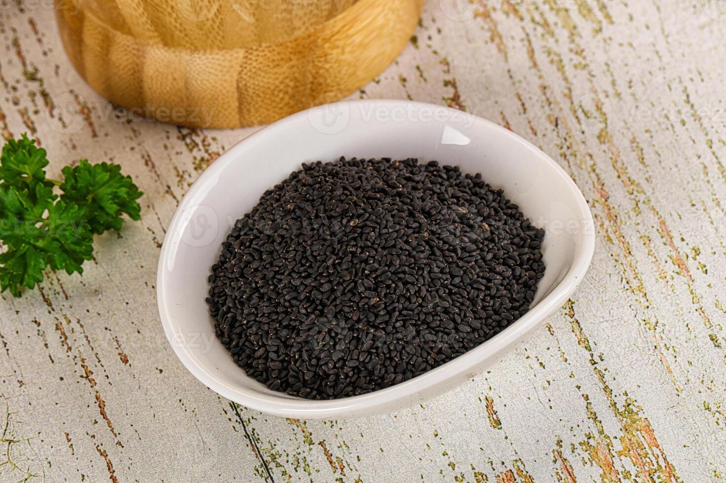 Black mustard seeds in a bowl on a wooden table photo