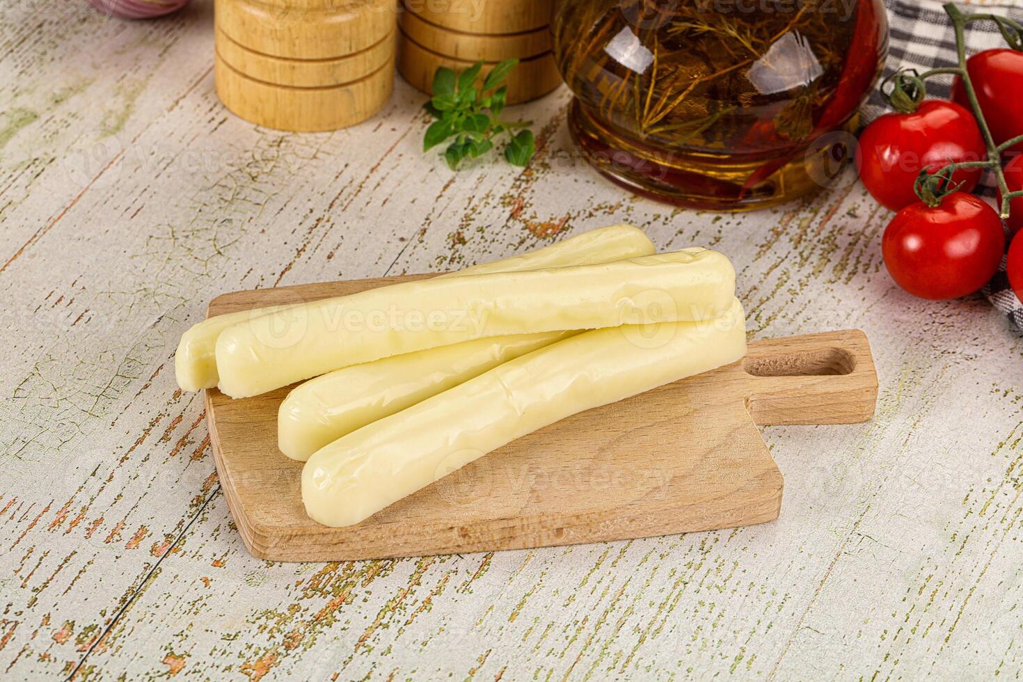 A wooden cutting board with cheese and tomatoes photo