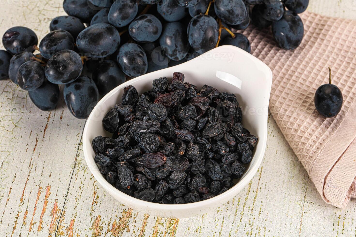 A bowl of black grapes and a towel on a table photo