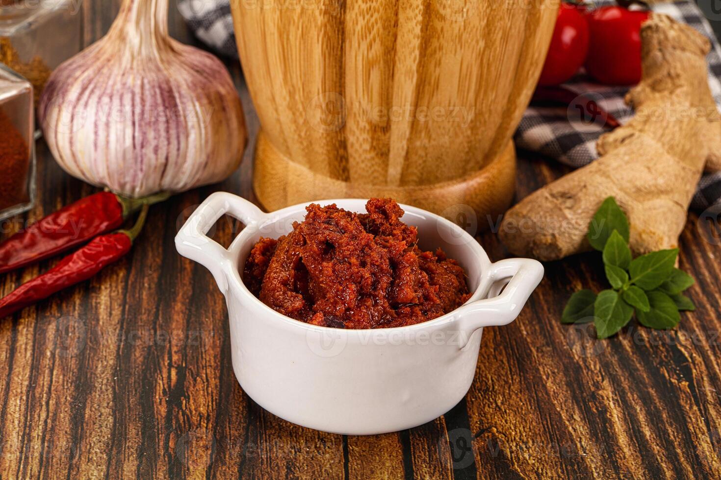 A bowl of chili sauce next to a bottle of garlic paste photo