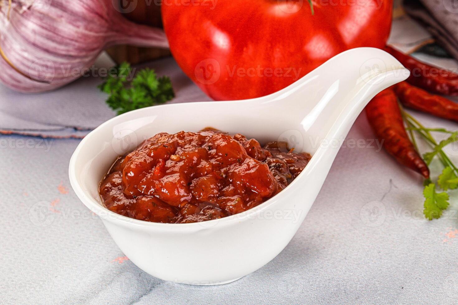 A white spoon with a small bowl of sauce photo