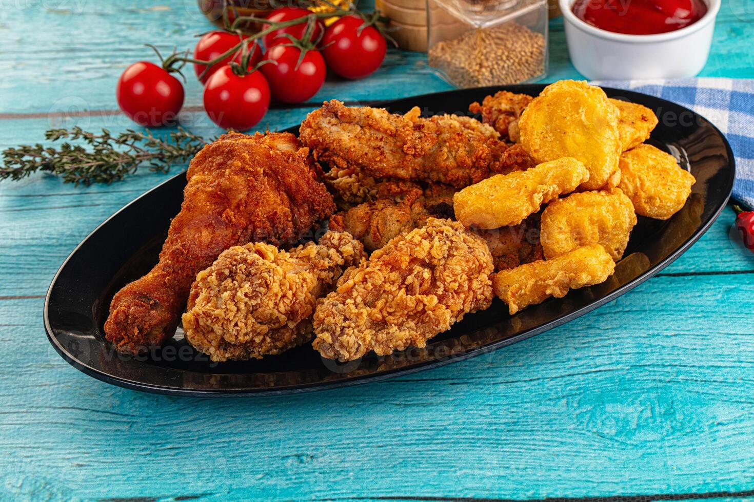 A plate of fried chicken, corn on the cob, and tomatoes photo