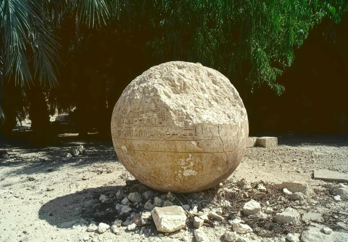 Ancient stone sphere with hieroglyphs in an outdoor setting photo